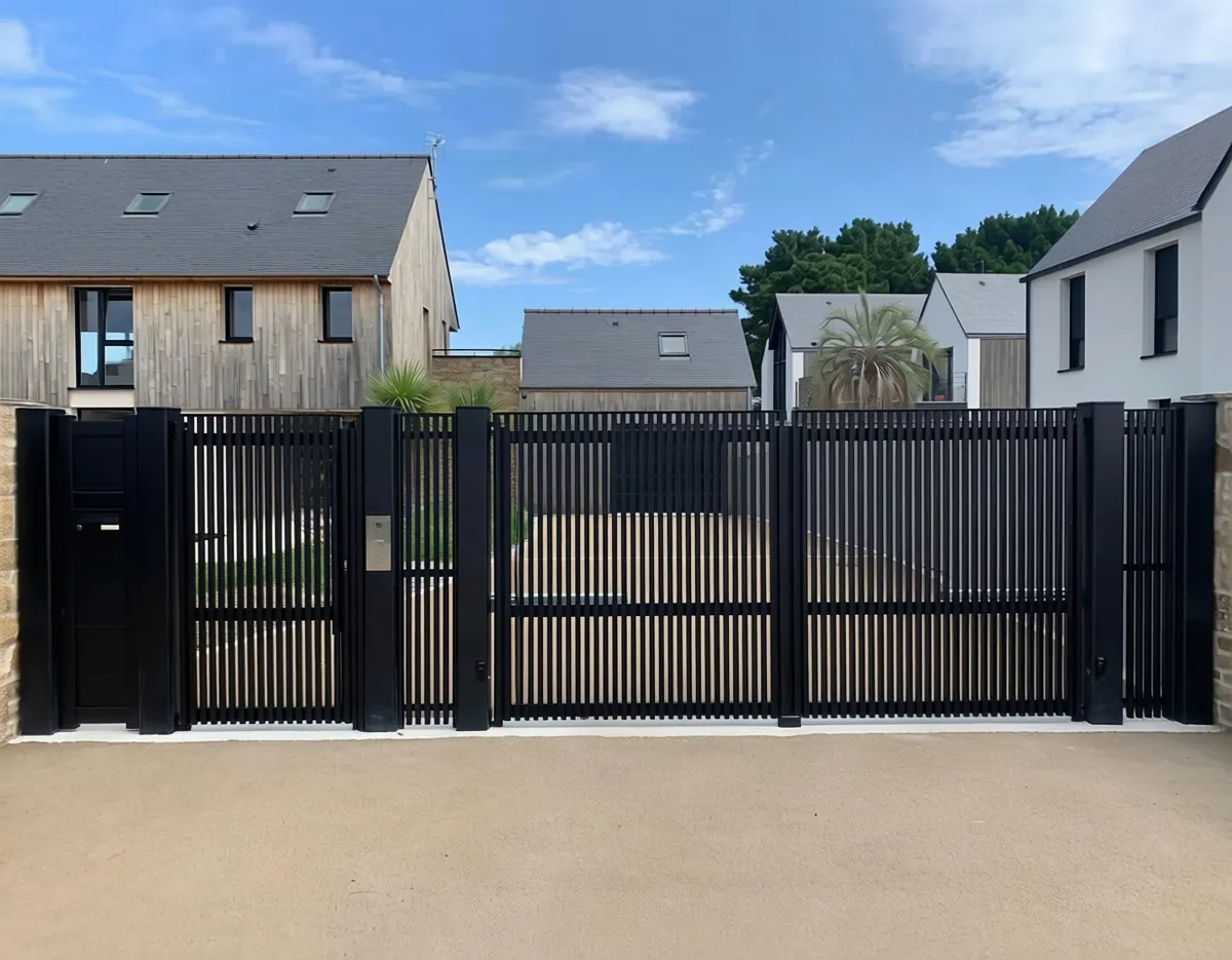 Portail aluminium ajouré noir à barreaux verticaux devant une maison